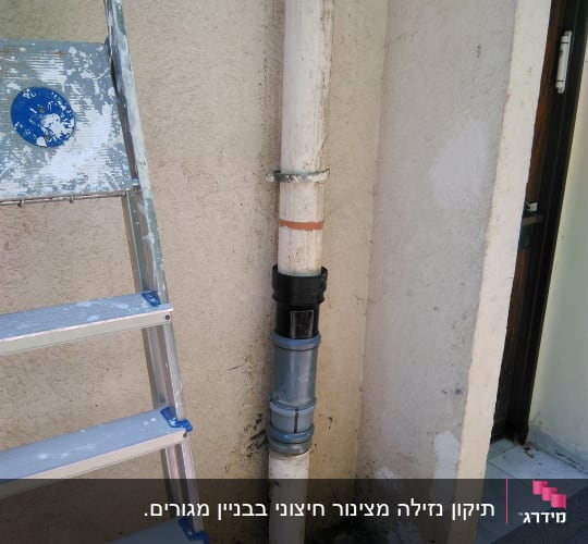 צינור מים עם חיבורי מתכת ליד סולם